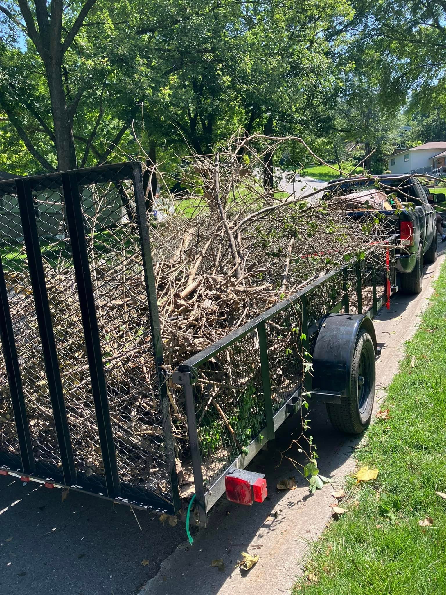 Open trailer loaded with brush and branches.