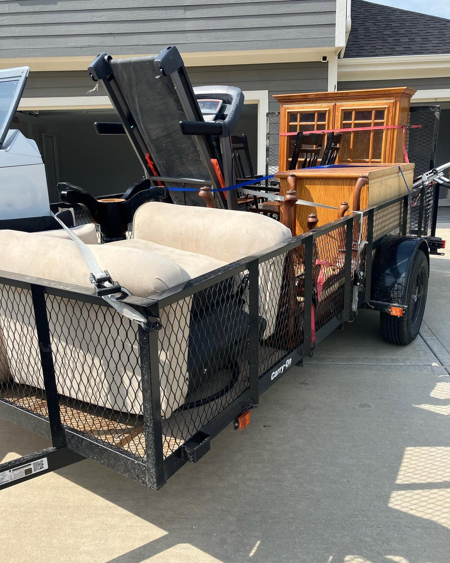 Trailer loaded with household furniture outside a home.